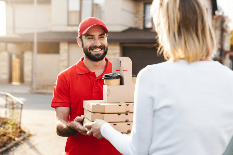 Delivery driver handing food and coffee order to customer using hands-free Philips TAL series wireless headset for delivery drivers