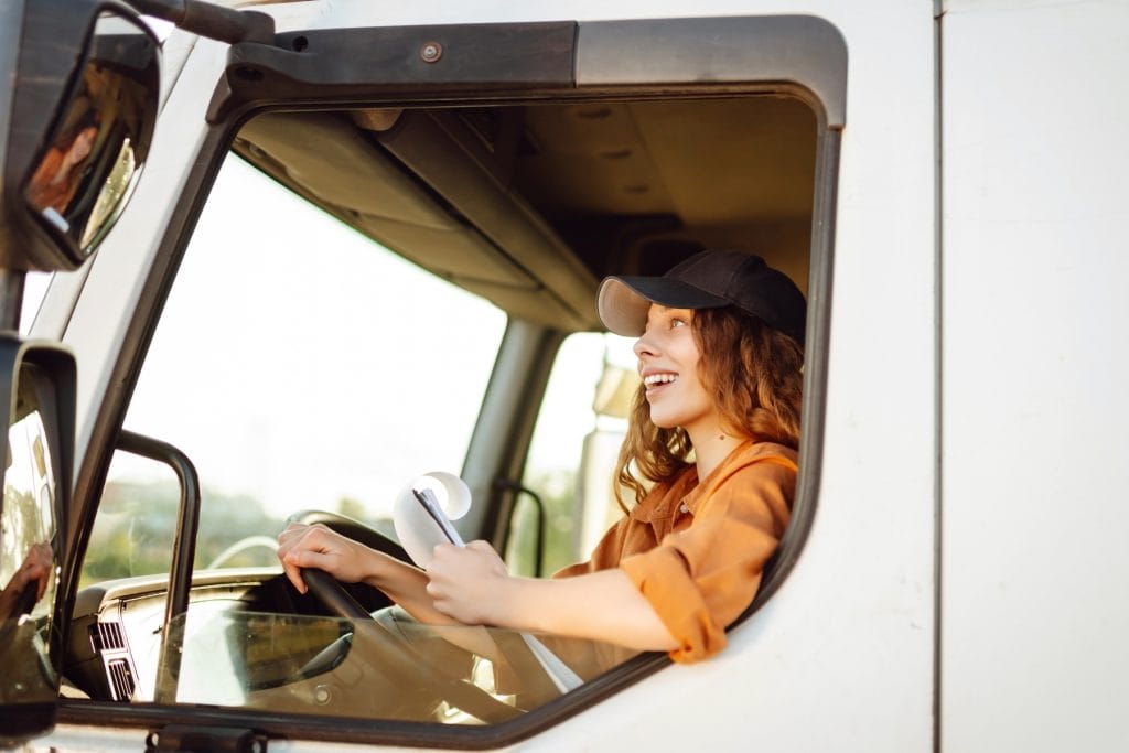 Female truck driver driving safely while using fleet communication solutions