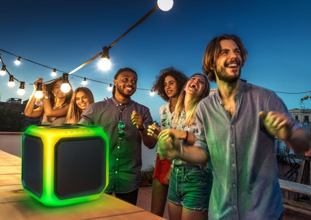 Friends dancing at an outdoor night party illuminated by a Philips light-up Bluetooth speaker