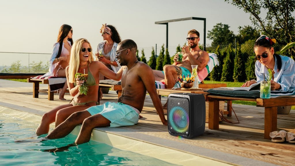 Philips TAX3000 party speaker with deep woofer bass placed poolside with friends relaxing