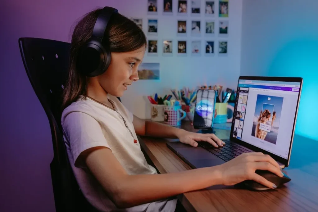 Girl wearing black headphones while using a laptop at a desk.