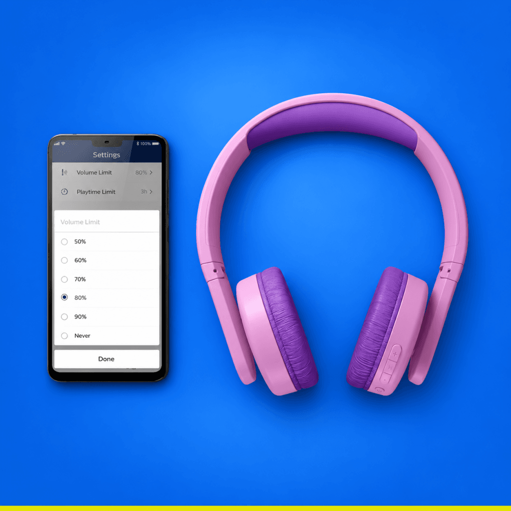Pink Philips TAK4206 kids headphones beside a phone displaying volume and playtime limit settings, on a blue background.